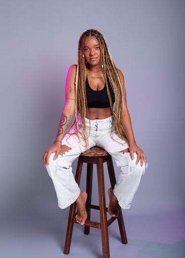 Brunette model with braids in her hair, wearing white...