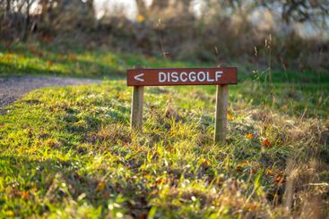 Sign pointing the way to a disc golf course.