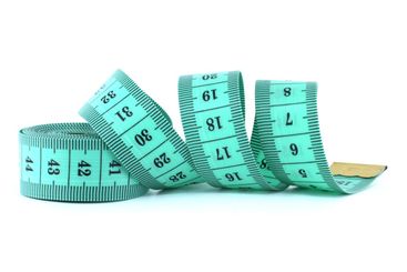 A light green measuring tape coiled on a white...