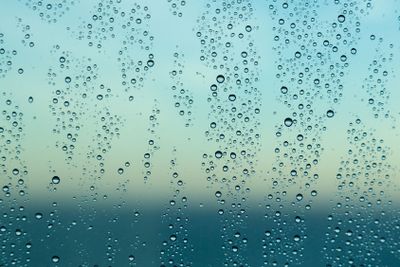 Raindrops on window of a ship at sea with horizon