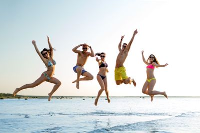 smiling friends in sunglasses on summer beach