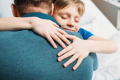 portrait of smiling little son hugging father in hospital...