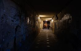 Dimly lit urban tunnel with graffiti and people under...