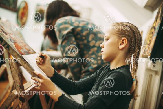 Beautiful teenage girl with pigtails at art school draws...