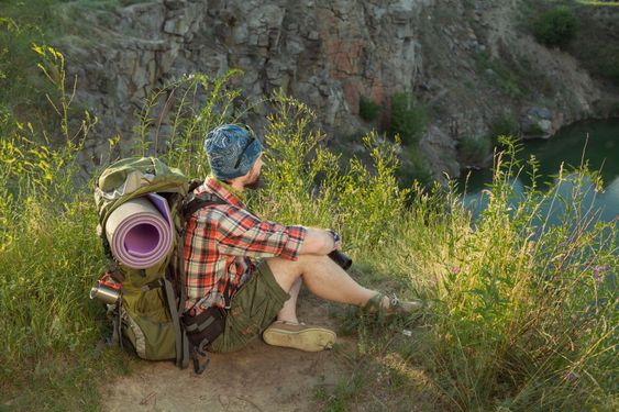 Young caucasian man with backpack sitting on the top of...