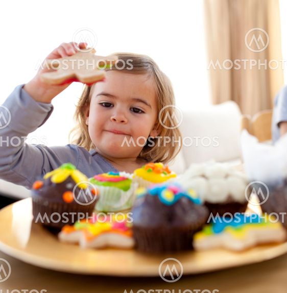 Happy little girl eating confectionery at home