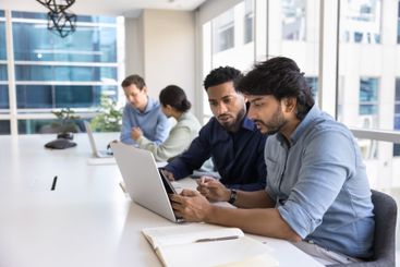 Two serious diverse male project managers talking at laptop