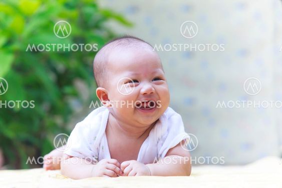 beautiful photo close up face of adorable new born baby smiling lovely emotion lying on soft clothes at home terrace