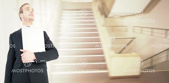 Composite image of businessman looking up holding laptop