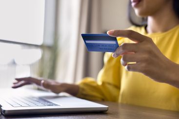 Woman using laptop, enter debit card details for...