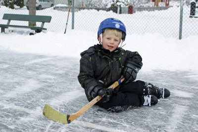 Liten pojke på sitter på isbana
