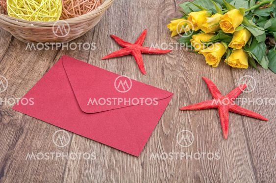 Envelope, starfishes and roses on a wooden background