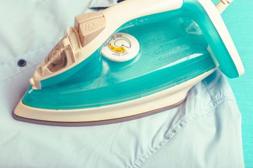 Iron on ironing board on light home interior background