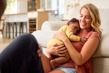 Family Shot With Parents Cuddling Baby Daughter Sitting...