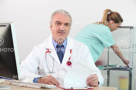 senior doctor in his surgery with nurse in background