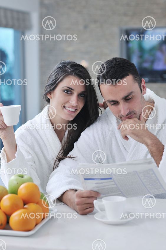 Happy couple reading the newspaper in the kitchen at breakfast