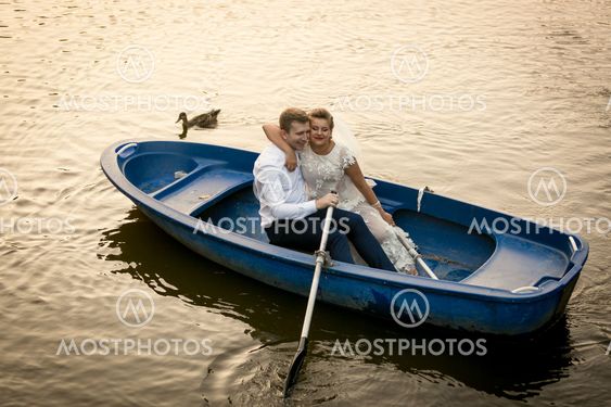 Smiling bride and groom embracing on the rowing boat