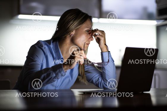 Pretty, middle-aged woman working late in the day on a...