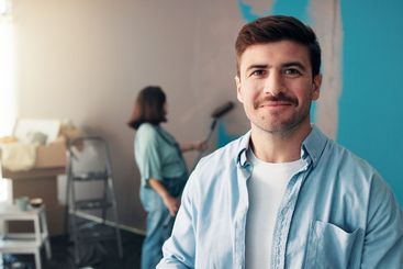 Portrait, smile and man in home for painting, wall...