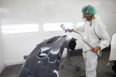 worker man spray painting on car body part in car...