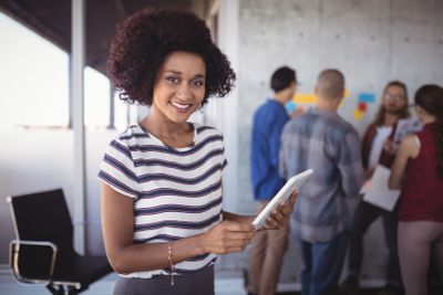 Female manager holding digital tablet while team...