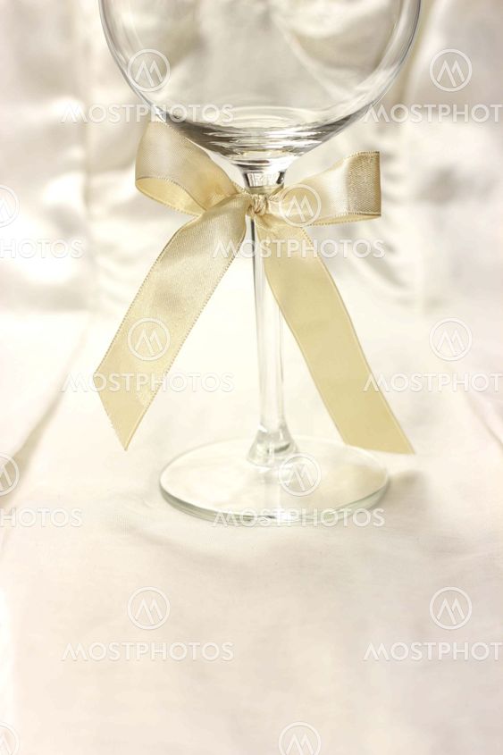 Wineglass with ribbon on silk fair background