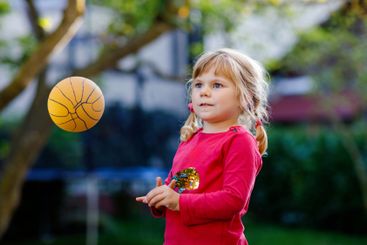 Little adorable toddler girl playing with ball outdoors....