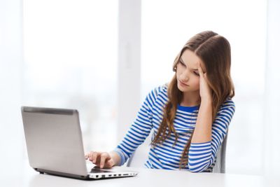 upset teenage gitl with laptop computer at home