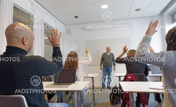 Elever med olika etnicitet räcker upp handen framför...