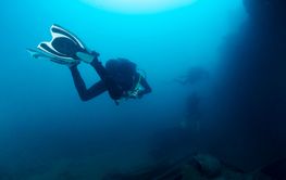 scuba diver diving a wreck in deep blue sea