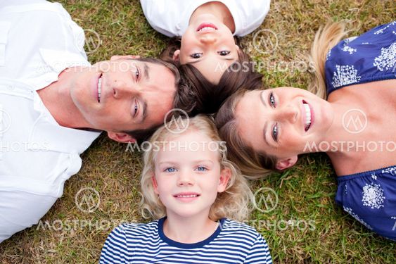 Loving family lying in circle on the grass
