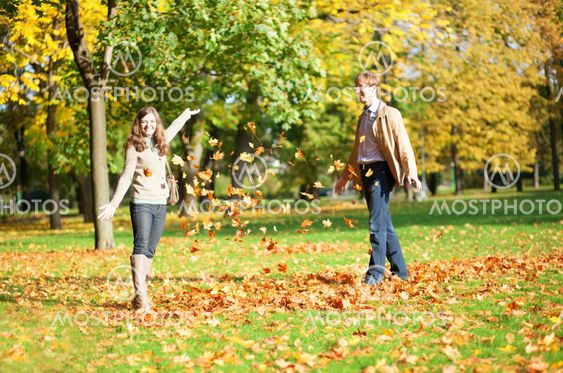 Cheerful couple playing with autumn leaves