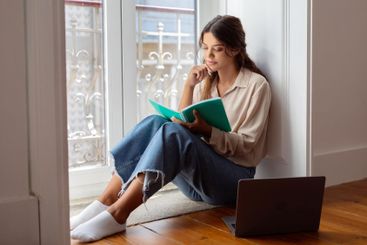 Concentrated young woman sitting on the floor with...