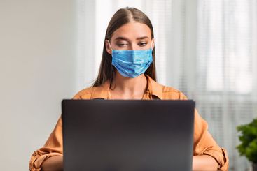 Woman in quarantine wearing face mask and working