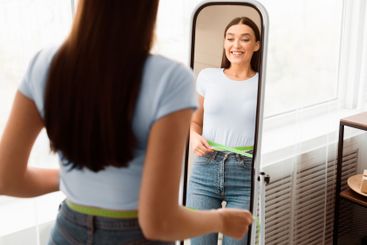 Excited Girl Measuring Thin Waist Looking In Mirror At Home