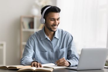 Smiling young male student wear earphones watch webinar...