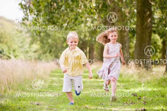 Two young children running on path smiling