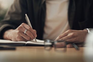 Hands, writing and notebook with planning in office with...