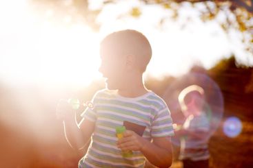 Sunlight, blowing bubbles and children in nature for...