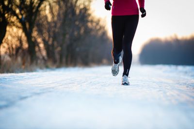 Winter running - Young woman running outdoors on a cold...