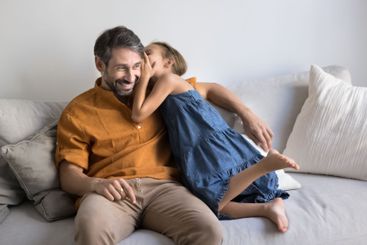 Cute little girl whispering on loving fathers ear a secret