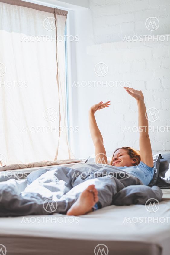 Young woman waking up lying in the bed