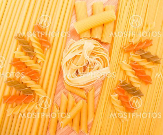 Different kinds of italian pasta on the wooden background