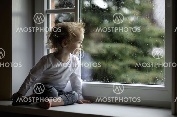 Adorable toddler girl looking at raindrops