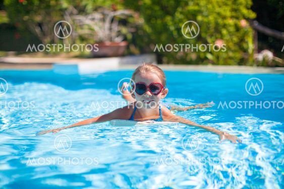 Little adorable happy girl swims in the swimming pool