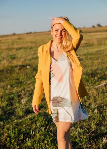 blonde woman in summer dress walking in blooming grass...