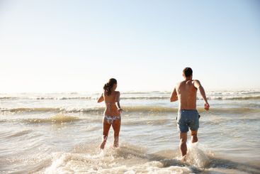 Beach, holiday and couple with waves, running and space...