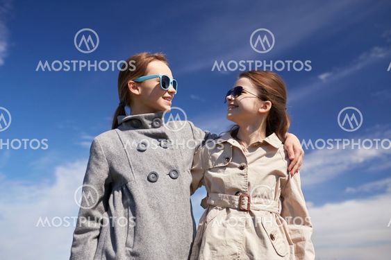 happy little girls hugging and talking outdoors