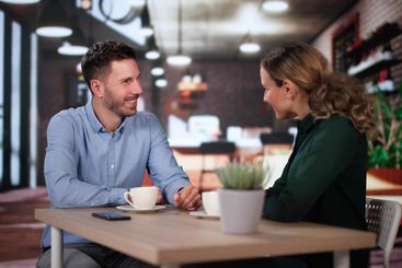 Laughing Male And Female Sitting In Cafe Drinking Coffee