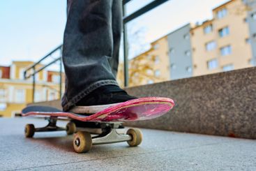 Skateboarder riding on pink skateboard at city street